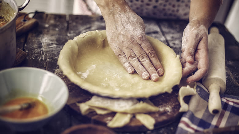 Hands molding homemade pie crust 