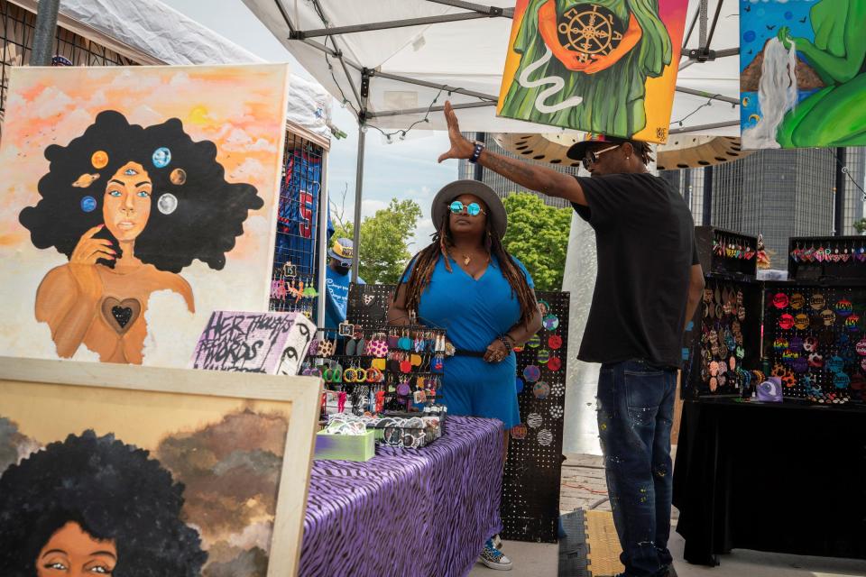 Detroit resident Viniecia Will, 38, left, gets assistance from Eric Brothers, 34, of Detroit displaying her artwork for her business, Nayetaye Visuals, that is created from recycled materials during the Wright's 39th African World Festival at Hart Plaza in Detroit on Friday, July 15, 2022.