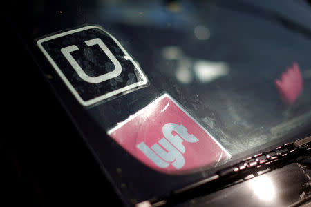 FILE PHOTO: A driver displays Uber and Lyft ride sharing signs in his car windscreen in Santa Monica, California, U.S., May 23, 2016. REUTERS/Lucy Nicholson/File Photo