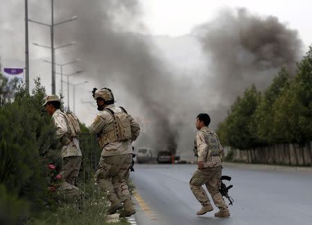 Members of Afghan security forces cross a road as smoke billows from the site of an attack near the Afghan parliament in Kabul, Afghanistan June 22, 2015. REUTERS/Ahmad Masood