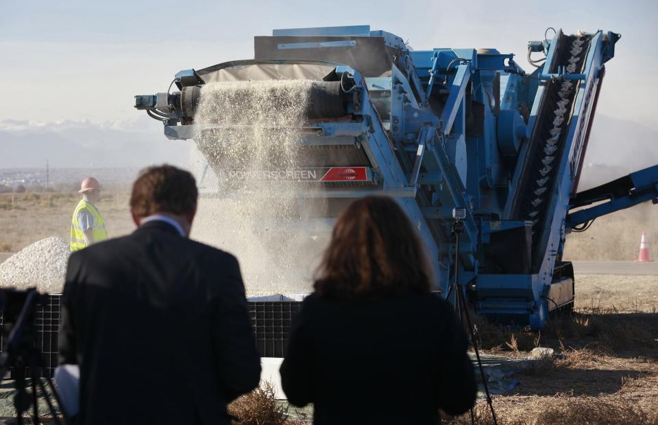 People watch as 6 tons of ivory are crushed by a rock crushing machine in Denver, Colorado