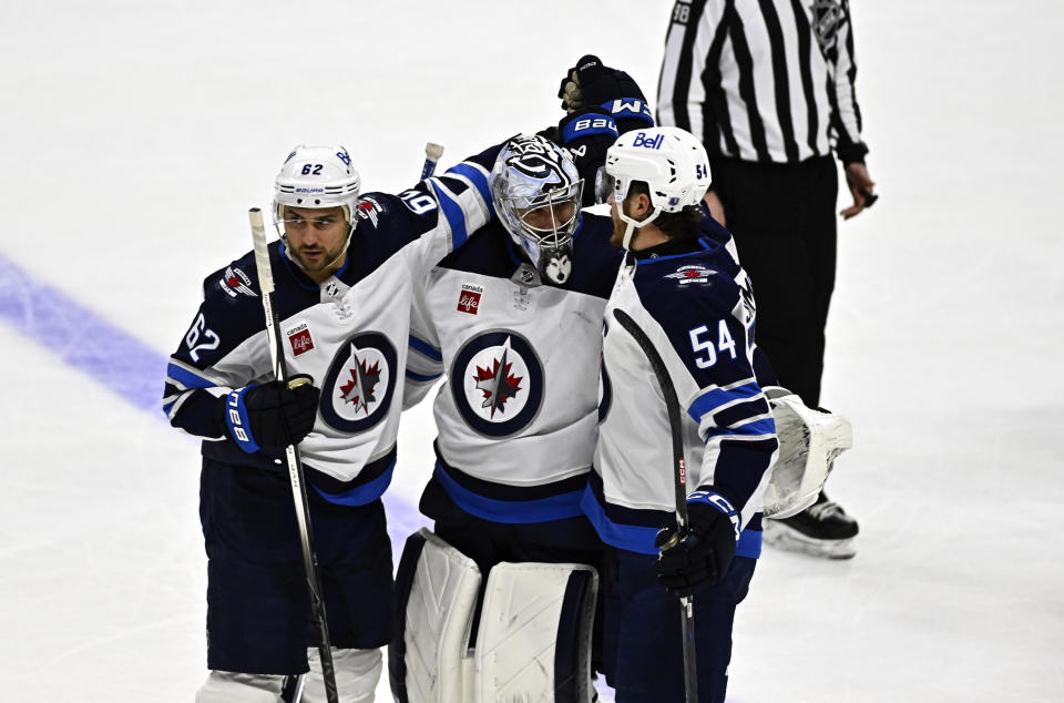 Winnipeg Jets goaltender Connor Hellebuyck (37) celebrates with right wing Nino Niederreiter (62) and defenseman Dylan Samberg (54) after the team's overtime win over the Ottawa Senators in an NHL hockey game, Saturday, Jan. 20, 2024, in Ottawa, Ontario. (Justin Tang/The Canadian Press via AP)