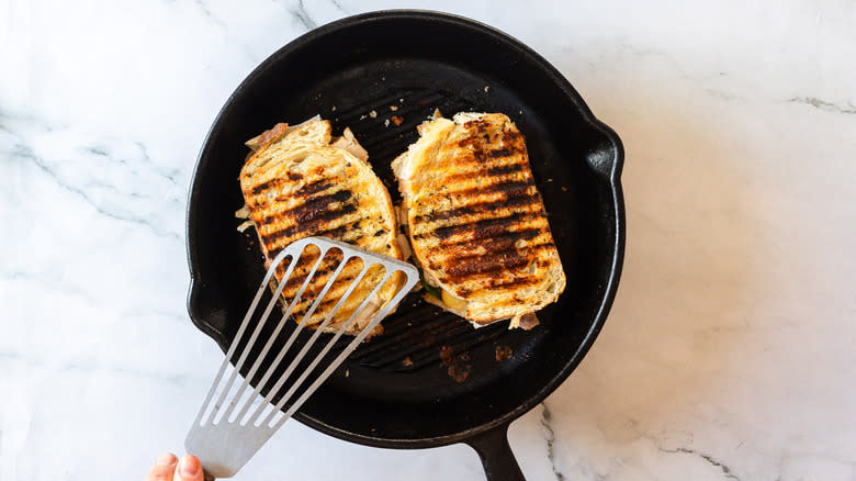 Pressing down grilled panini sandwiches in pan