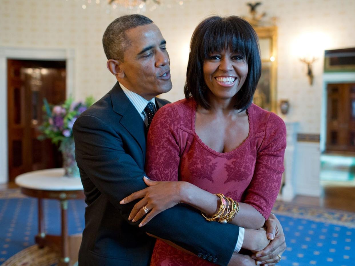 Barack Obama hugs Michelle Obama, who is sporting bangs, in the Blue Room of the White House in 2013.