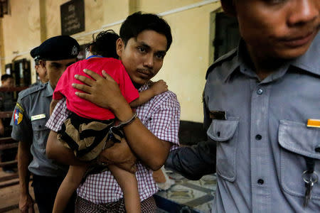 Detained Reuters journalist Kyaw Soe Oo carries his daughter Moe Thin Wai Zin while escorted by police during a court hearing in Yangon, Myanmar June 18, 2018. REUTERS/Ann Wang