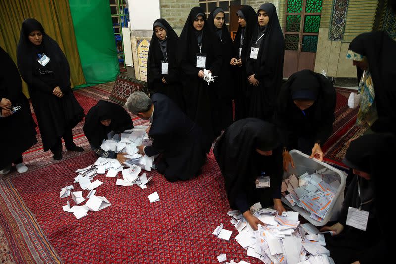 Poll workers empty full ballot boxes after the parliamentary election voting time ended in Tehran