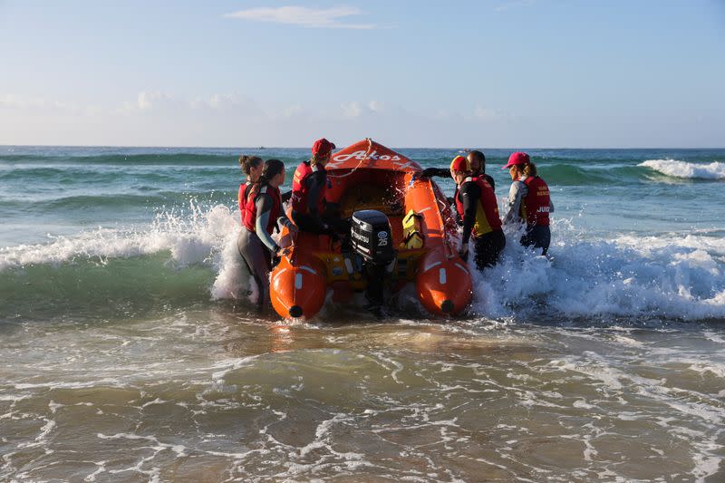 IRB Racing team carries a boat into the ocean on Bondi Beach