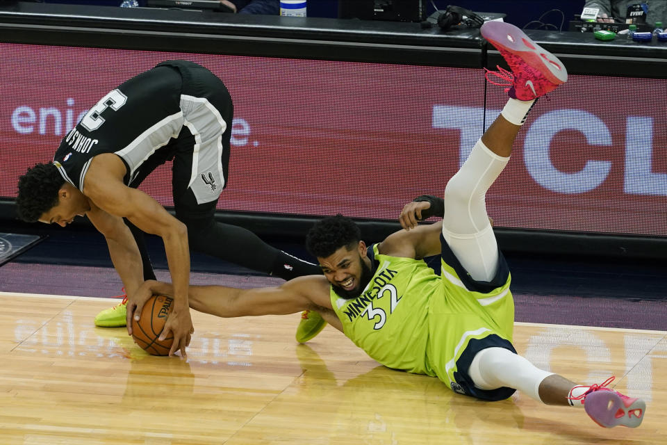 Minnesota Timberwolves' Karl-Anthony Towns , right, sprawls on the court and tries to get the ball away from San Antonio Spurs' Keldon Johnson in the second half of an NBA basketball game Saturday, Jan. 9, 2021, in Minneapolis. (AP Photo/Jim Mone)