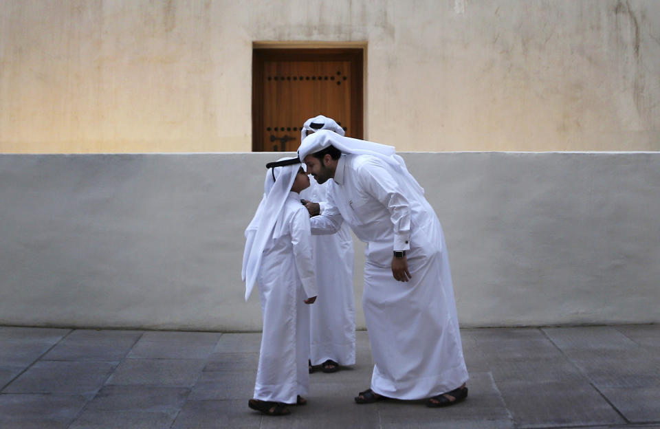 FILE - A Qatari man greets a boy in traditional Gulf Arab style during an event in the Msheireb district of Doha, Qatar, May 6, 2018. Qatar has sought to portray itself as welcoming foreigners to this hereditarily ruled emirate, where traditional Muslim values remain strong.(AP Photo/Kamran Jebreili, File)