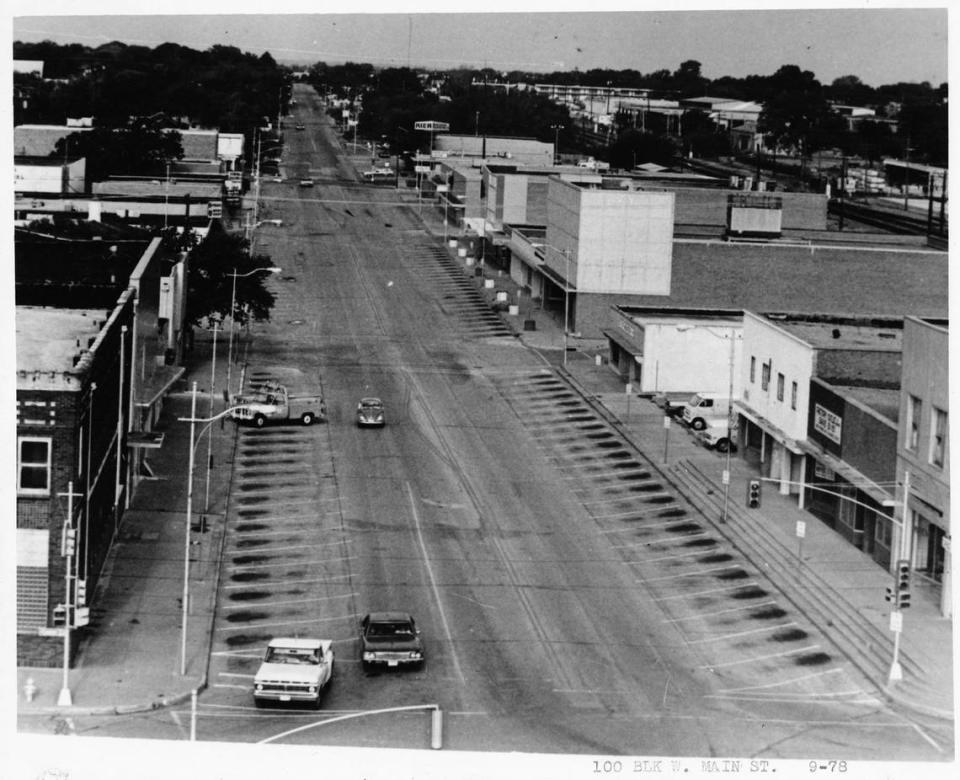 1978: The 100 block West Main St., Arlington, Texas. There are some cars driving down the street.
