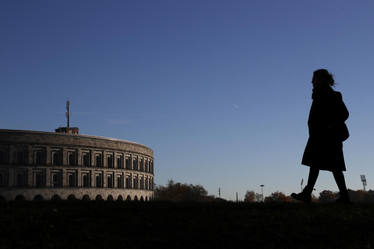 A woman passes the 'Congress Hall' at the 'Reichsparteigelande' (Nazi Party Rally Grounds) in Nuremberg, Germany, Wednesday, Nov. 18, 2020. Germany marks the 75th anniversary of the landmark Nuremberg trials of several Nazi leaders and in what is now seen as the birthplace of a new era of international law on Friday, Nov. 20, 2020.(AP Photo/Matthias Schrader)