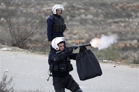 A Palestinian policeman fires tear gas towards demonstrators outside the Jalazoun refugee camp near the West Bank city of Ramallah January 12, 2014. REUTERS/Mohamad Torokman