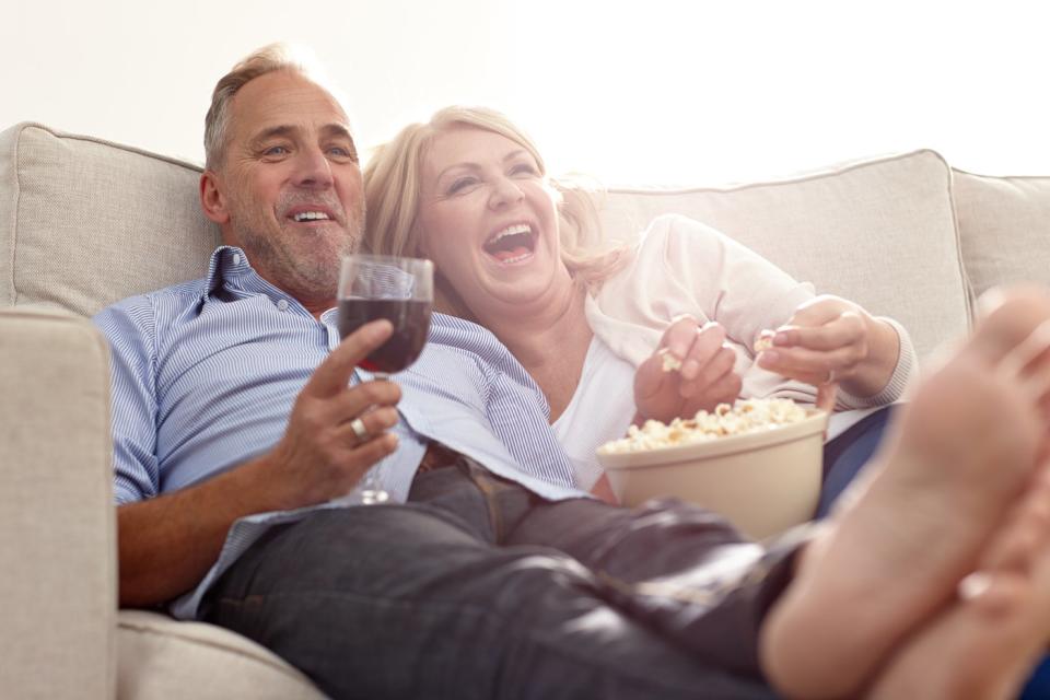 Two people relaxing on a couch watching television.