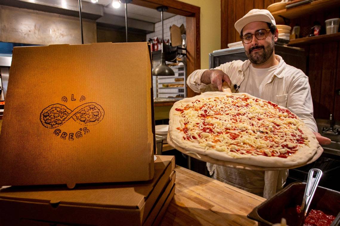 Greg Tetzner, owner of Old Greg’s Pizza restaurant, holds out a pizza pie ready for the oven inside his brick and mortar in Midtown.