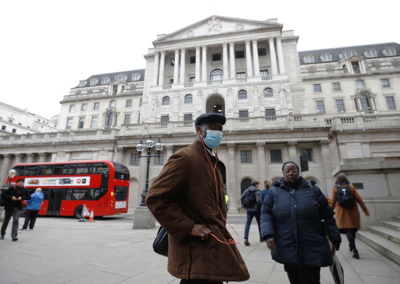 A man, wearing a protective face mask, walks in front of the Bank of England, following an outbreak of the coronavirus, in London