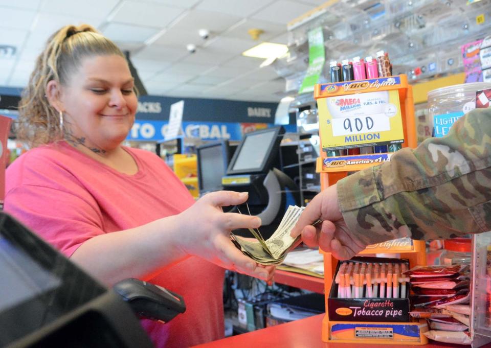 Clerk Kristin DeShong takes money from Gary Thorstenson, of Griswold, for four Mega Millions lottery tickets Thursday at the Global Gas station on West Town Street in Norwich. [John Shishmanian/ NorwichBulletin.com]