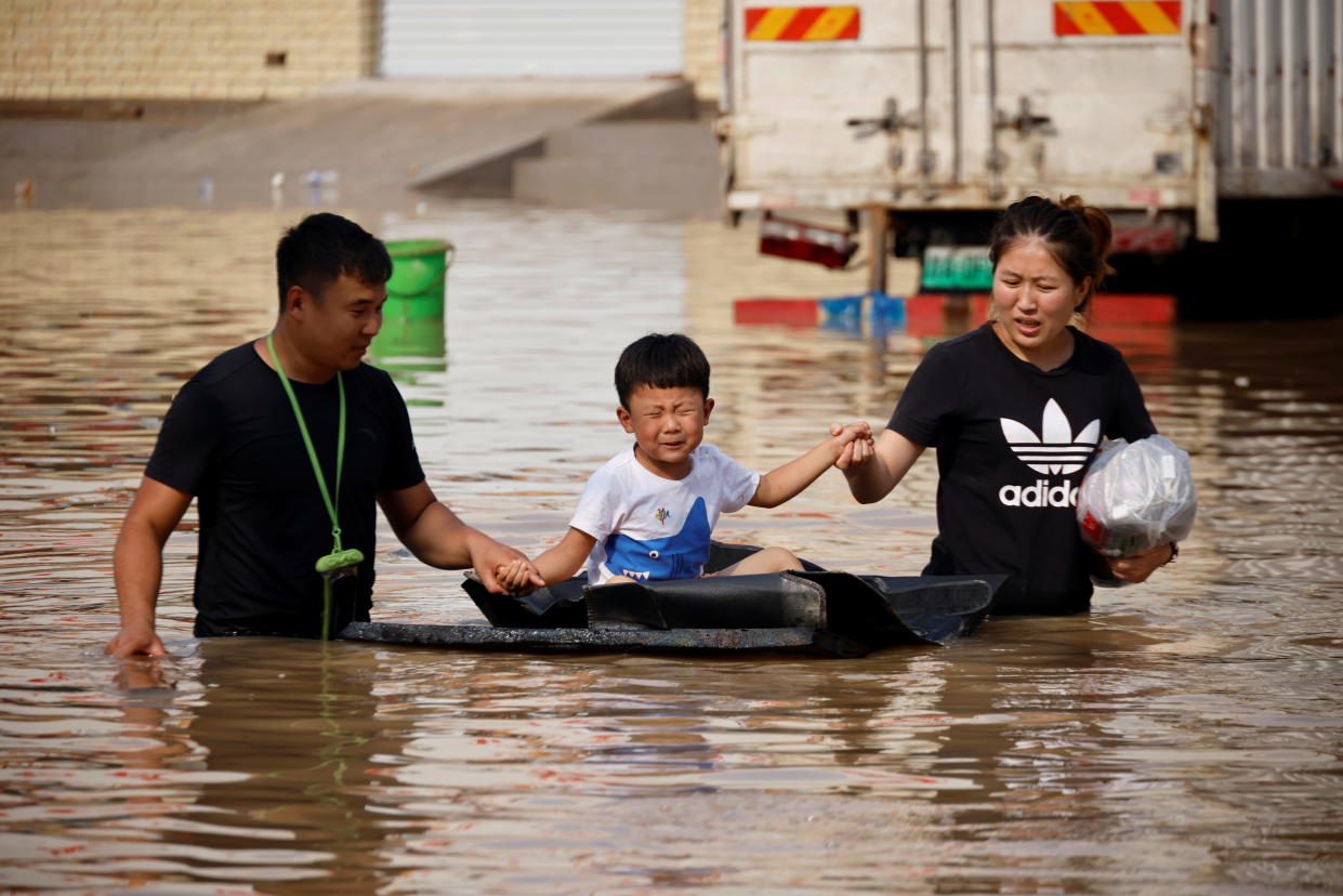 A child sits on a makeshift raft on a flooded road following heavy rainfall in Zhengzhou, Henan province, China July 22, 2021.  REUTERS/Aly Song