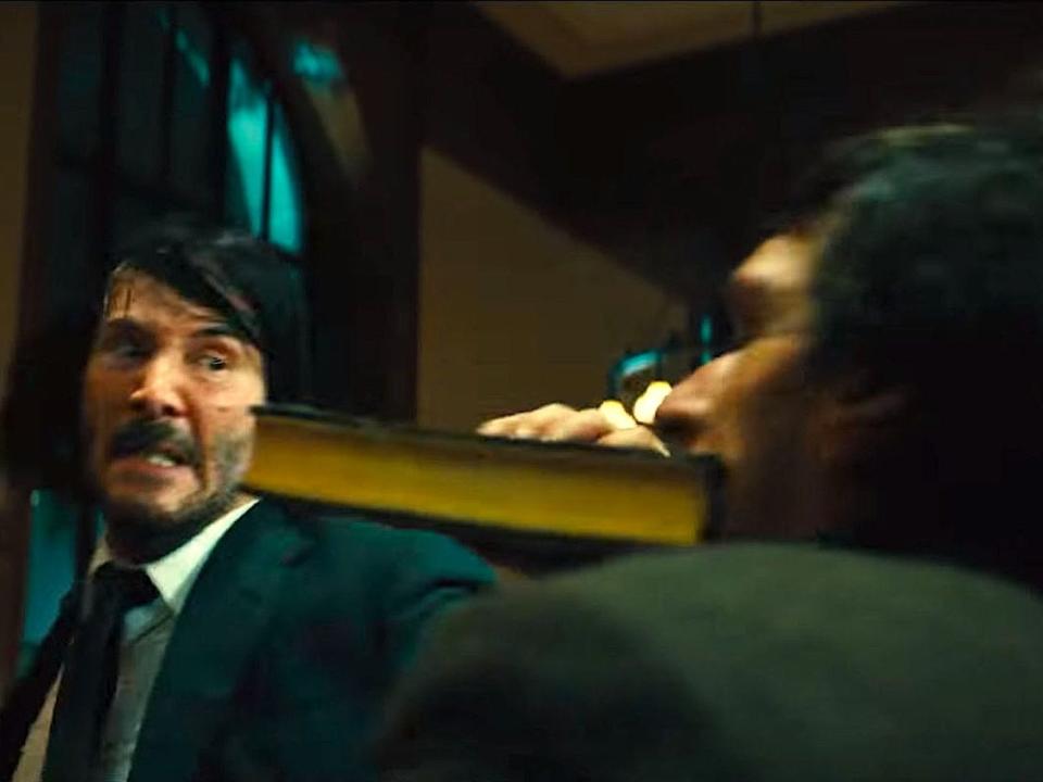 Keanu Reeves as John Wick hitting Boban Marjanović as Ernest with a book.