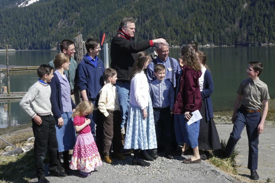 Alaska Gov. Mike Dunleavy, center, gathers with members of Mark and Amy Bach's family as they prepare to pose for a photo on Thursday, April 22, 2021, in Hyder, Alaska. The family also invited Dunleavy to their home before he left Hyder, a small community near the U.S.-Canada border and one of the stops on Dunleavy's one-day visit to southeast Alaska communities on April 22, 2021. (AP Photo/Becky Bohrer)