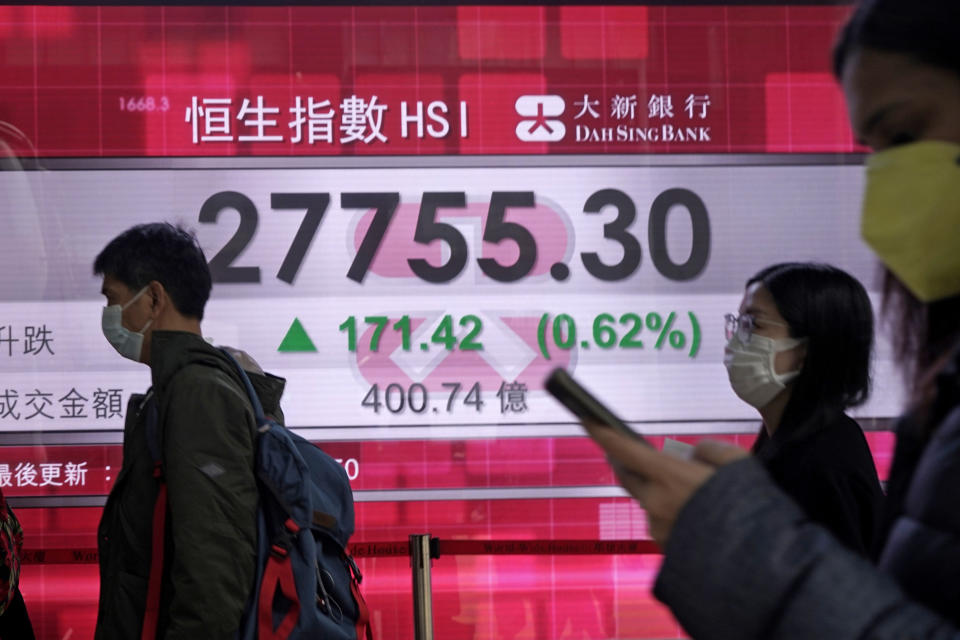 People walk past an electronic board showing Hong Kong share index outside a local bank in Hong Kong, Wednesday, Feb. 12, 2020. Asian shares were higher Wednesday, although the outbreak of a new virus in the region continued to weigh on investor sentiments. (AP Photo/Kin Cheung)