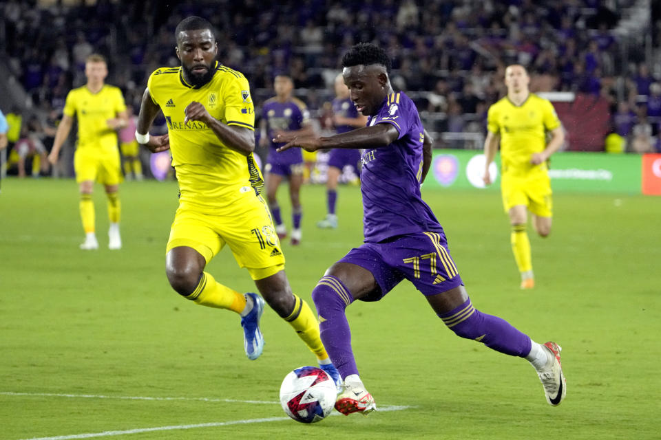 Orlando City forward Ivan Angulo (77) moves the ball to the goal against Nashville SC defender Shaq Moore (18) during the second half of an MLS playoff soccer match, Monday, Oct. 30, 2023, in Orlando, Fla. (AP Photo/John Raoux)