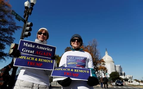 Protesters hold placards outside of the Longworth building, where the hearing took place - Credit: Reuters