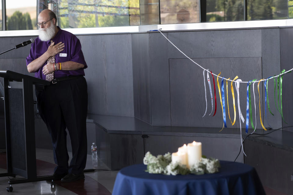 In this image provided by WSU College of Veterinary Medicine, Scott Campbell, the Veterinary Chaplain at Washington State University's College of Veterinary Medicine, speaks during a "Celebration of Life & Remembrance for Our Companion Animals" event on Saturday, July 15, 2023, in Pullman. Wash. At right are ribbons honoring pets that have passed away that were hung as part of the Garland Ceremony, and now are displayed next to a bench at the entrance to the Veterinary Teaching Hospital. (Ted S. Warren/WSU College of Veterinary Medicine via AP)