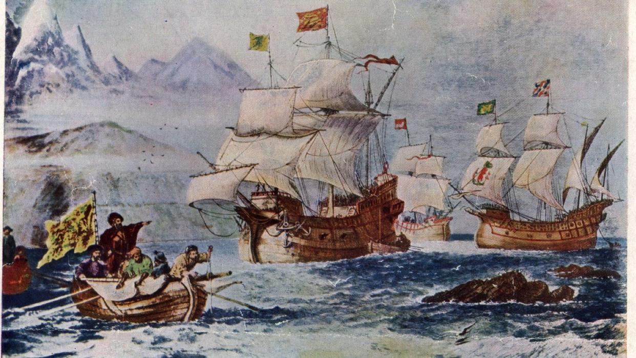 ferdinand magellan with a crew of men sailing in a small boat as large ships wait in the background