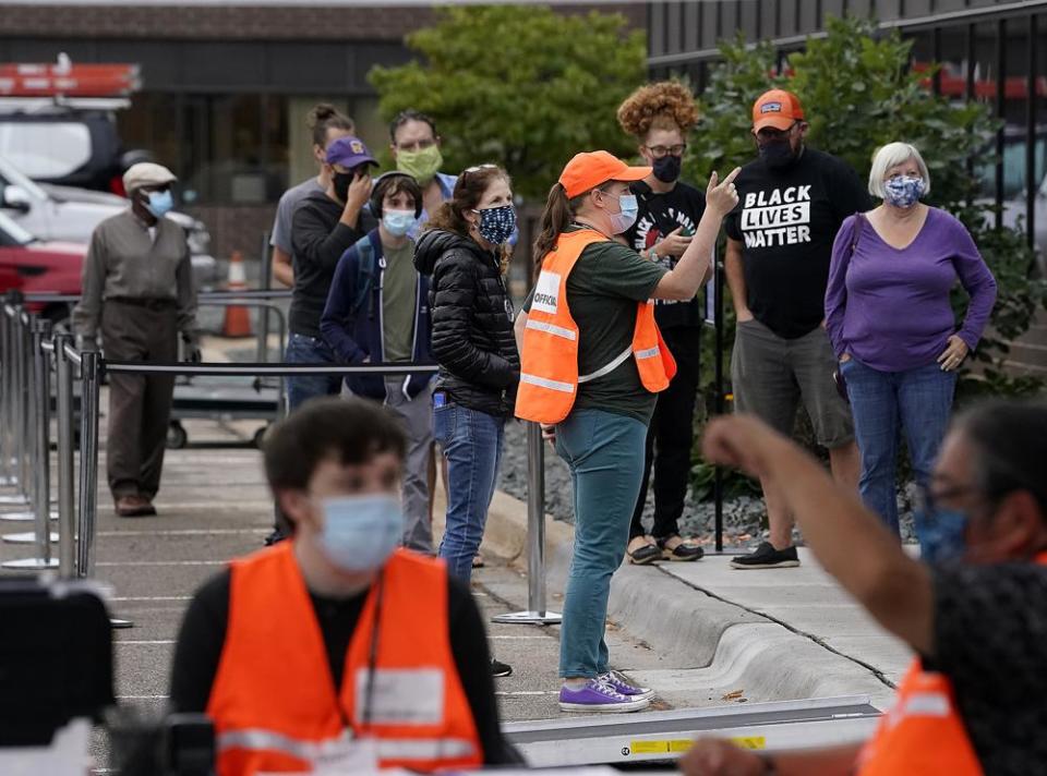 Election worker Angelina Vyushkova, in orange vest, instructs people waiting in line during the first day of early voting at Minneapolis Elections and Voter Services on Sept. 17.