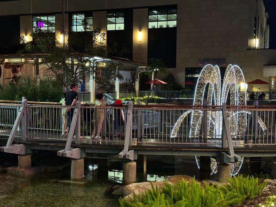 Una familia contempla el nuevo gimnasio estilo resort Life Time y la decoración navideña desde un puente del centro comercial The Falls un sábado por la noche, el 25 de noviembre de 2023.