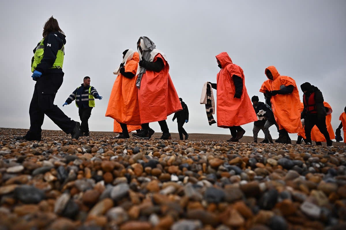 Immigration officers escort migrants on the shore at Dungeness (AFP/Getty)