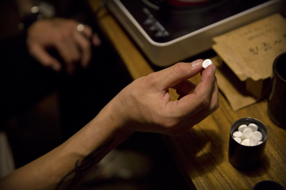 In this March 27, 2019, photo, Yin Hao, who also goes by Yin Qiang, holds a Tylox pill while sitting in a restaurant in Xi'an, in northwestern China's Shaanxi Province. Officially, pain pill addiction is an American problem, not a Chinese one. But people in China have fallen into opioid abuse the same way many Americans did, through a doctor's prescription. And despite China's strict regulations, online trafficking networks, which facilitated the spread of opioids in the U.S., also exist in China. (AP Photo/Mark Schiefelbein)
