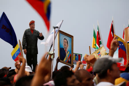 Supporters of Venezuela's President Nicolas Maduro holding a cardboard cut-out and a painting depicting Venezuela's late President Hugo Chavez attend a campaign rally in La Guaira, Venezuela May 2, 2018. REUTERS/Carlos Garcia Rawlins