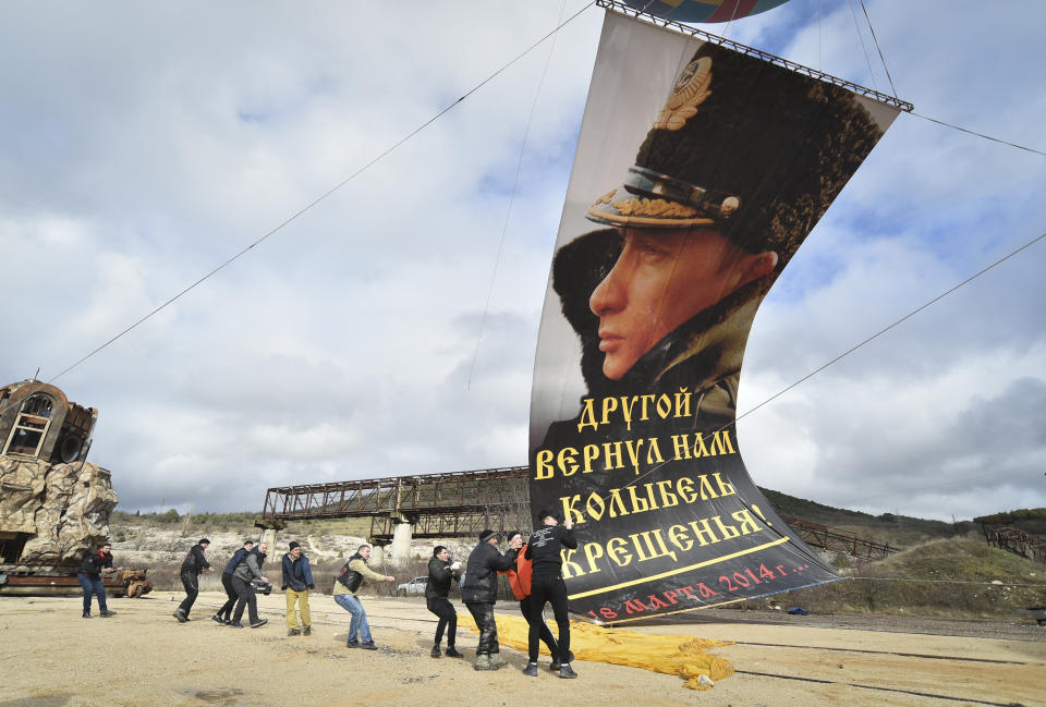 Enthusiasts fix a portrait of Russian President Vladimir Putin to a balloon during celebration of the anniversary of Crimea annexation from Ukraine in 2014, in Sevastopol, Crimea, Thursday, March 18, 2021. Residents of cities in Crimea and Russia are holding gatherings to commemorate the seventh anniversary of Russia's annexation of the Black Sea peninsula from Ukraine. The sign reading "Another gave us back the cradle of baptism. March 18, 2014". (AP Photo)