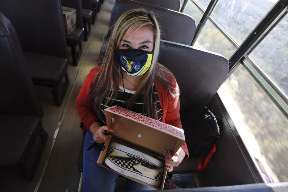 Social worker Victoria Dominguez brings shoes to a student who has dwelled on suicide, as she rides a school bus along a dirt road outside Cuba, N.M., Oct. 19, 2020. The switch to remote learning in rural New Mexico has left some students profoundly isolated — cut off from others and the grid by sheer distance. The school system is sending school buses to students’ far-flung homes to bring them assignments, meals and a little human contact. (AP Photo/Cedar Attanasio)