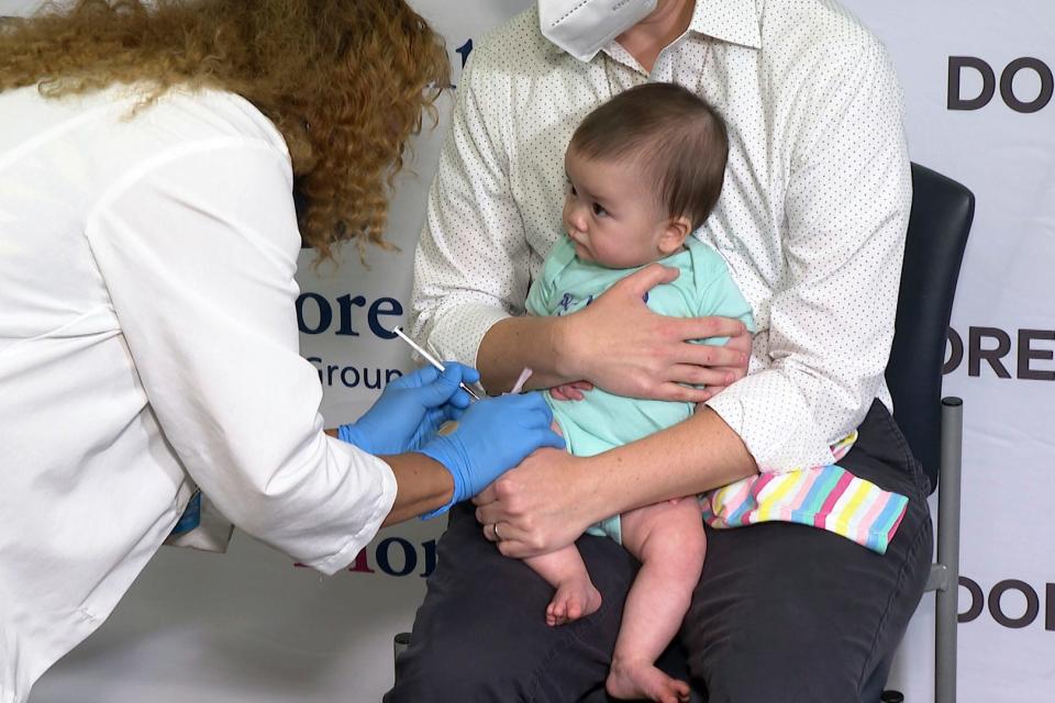 Ellen Fraint holds her daughter, seven-month-old Jojo, as she receives the first dose of the Moderna COVID-19 vaccine for children at Montefiore Medical Group in the Bronx borough of New York City on June 21, 2022.