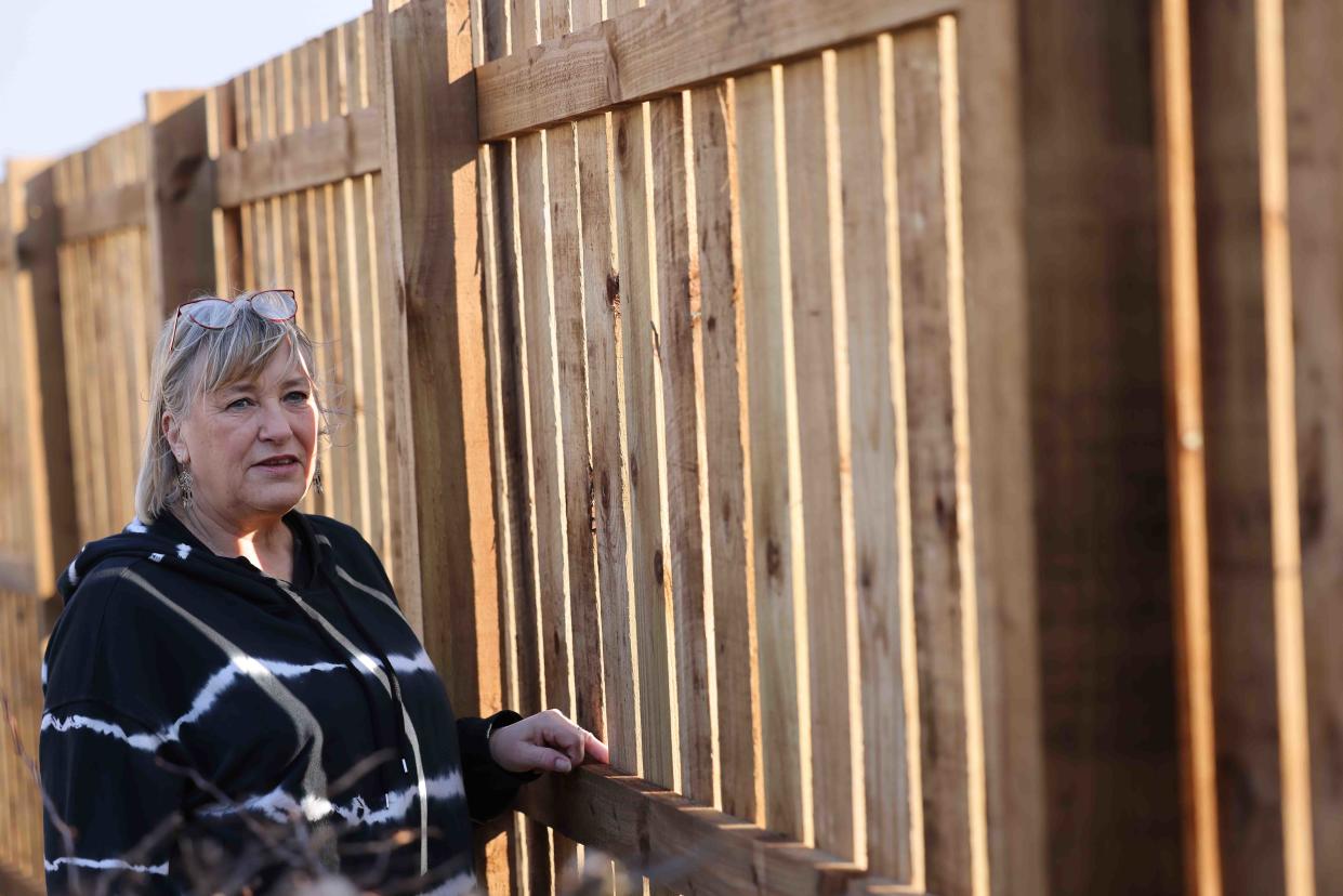 Lorraine Twizell in front of the two-metre fence: 'The whole village is very angry.' (Reach)