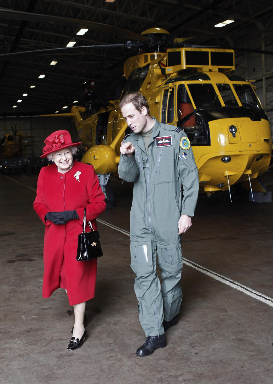 ARCHIVO - La reina Isabel II de Gran Bretaña es escoltada por el príncipe Guillermo durante una visita a RAF Valley, Anglesey, Gales, donde él está estacionado como piloto de helicóptero de búsqueda y rescate, el 1 de abril de 2011. (Christopher Furlong, Pool Photo vía AP, archivo)