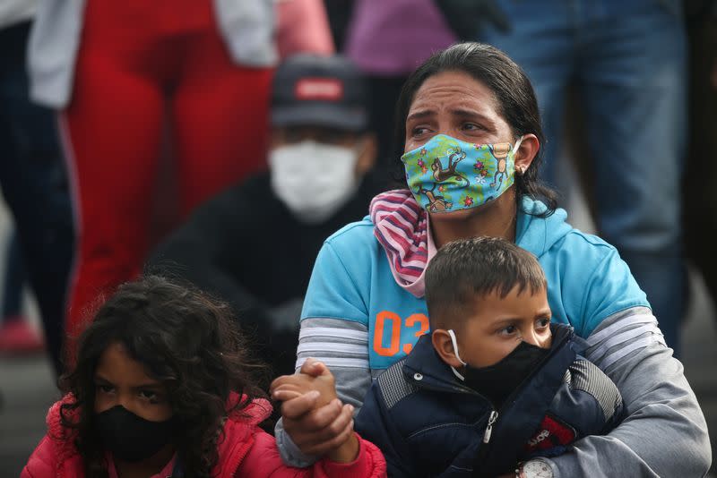 Foto de archivo. Una mujer migrante venezolana con mascarilla sostiene a un niño mientras participa en una protesta contra el bloqueo de los autobuses que los migrantes contrataron para llegar a la frontera entre Colombia y Venezuela, en medio de la pandemia del COVID-19 en Bogotá