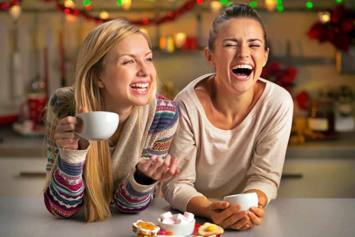 Two girls laughing and drinking coffee during holidays