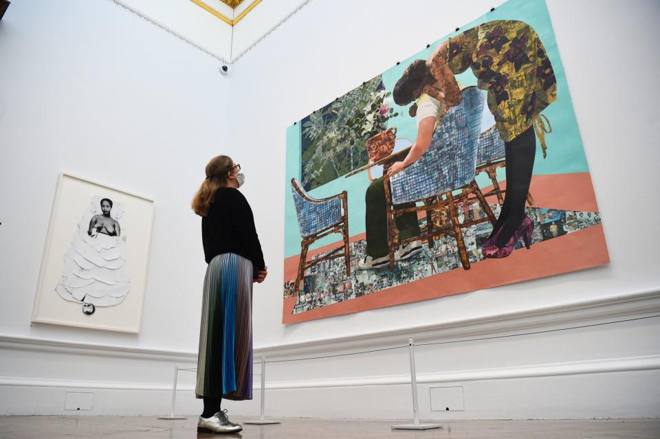 The two rooms dominated by the work of black artists offer resilience and energy: a member of staff inspects 'Blend In - Stand Out' by Njideka Akunyili Crosby - Kirsty O'Connor