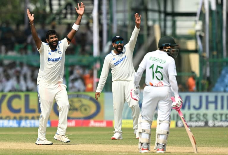 Jasprit Bumrah celebrates the wicket of Bangladesh's Taijul Islam with captain Rohit Sharma (Money SHARMA)