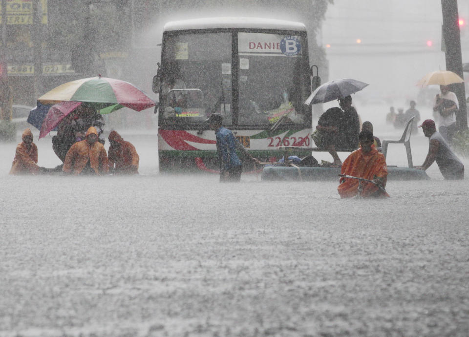 Office workers cross a flooded street using makeshift floats during heavy rain at the financial district of Makati, south of Manila, Philippines on Tuesday, Aug. 20, 2013. Flooding caused by some of the Philippines' heaviest rains on record submerged more than half the capital Tuesday, turning roads into rivers and trapping tens of thousands of people in homes and shelters. The government suspended all work except rescues and disaster response for a second day. (Aaron Favila/AP)