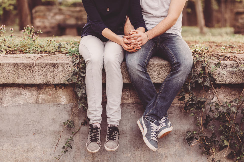 Cropped photo of young couple holding hands. (Getty Images).