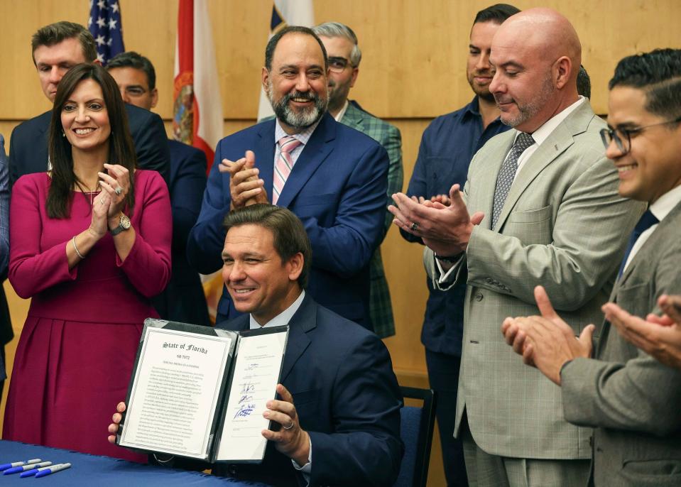 Florida Gov. Ron DeSantis hold up the signed legislation that seeks to punish social media platforms that remove conservative ideas.