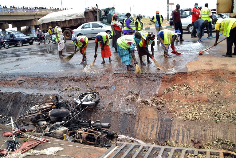 Nigerian workers clean the site of a bomb blast in Abuja on April 15, 2014