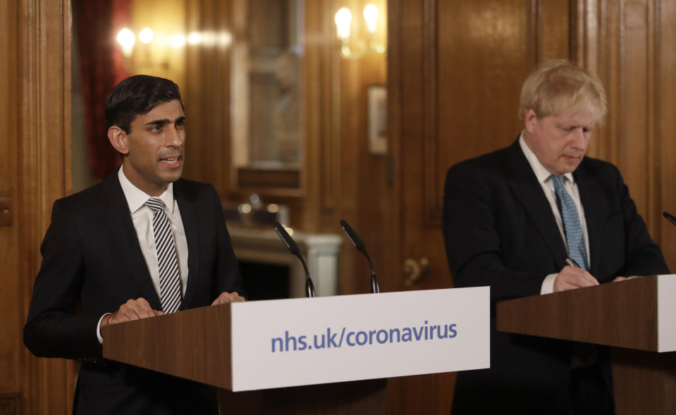 Britain's Chancellor Rishi Sunak, left, is flanked by British Prime Minister Boris Johnson as he gives a press conference inside 10 Downing Street in London, Tuesday, March 17, 2020 about the ongoing situation with the COVID-19 coronavirus outbreak. For most people, the new coronavirus causes only mild or moderate symptoms, such as fever and cough. For some, especially older adults and people with existing health problems, it can cause more severe illness, including pneumonia. (AP Photo/Matt Dunham, Pool)