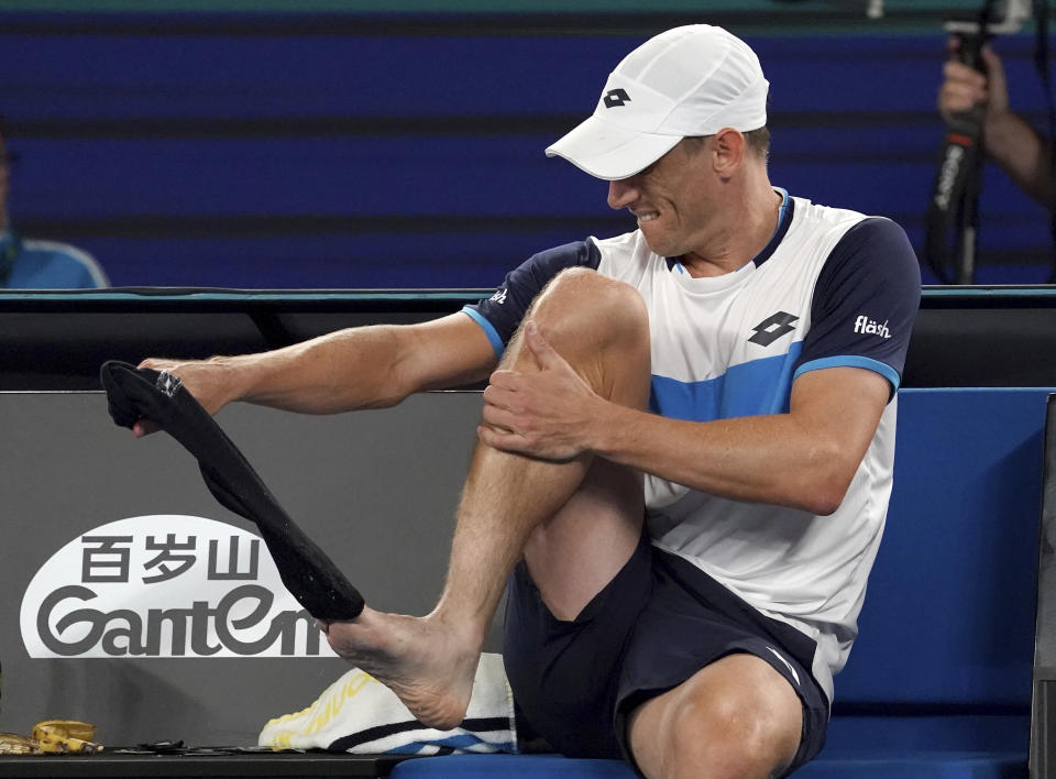 Australia's John Millman changes his socks during a break in his third round match against Switzerland's Roger Federer at the Australian Open tennis championship in Melbourne, Australia, Friday, Jan. 24, 2020. (AP Photo/Lee Jin-man)