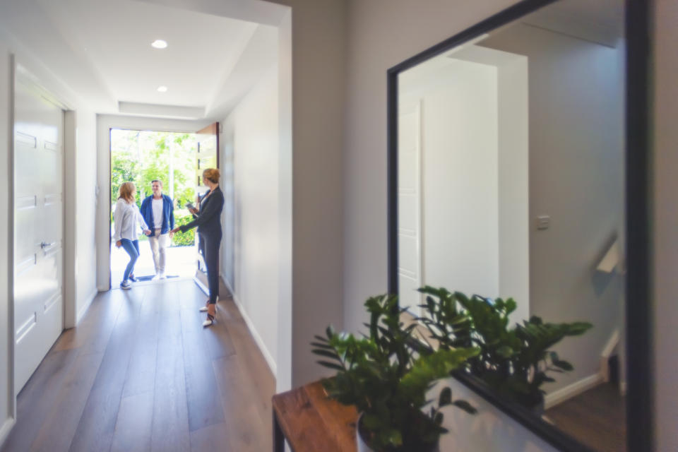 Real estate agent showing a young couple a new house. (Source: Getty)