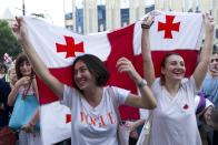 Opposition demonstrators wave Georgian national flags as they gather in front of the Georgian Parliament building in Tbilisi, Georgia, Monday, June 24, 2019. Demonstrators have returned to parliament for daily rallies, demanding the release of those detained, the ouster of the nation's interior minister and changes in the electoral law to have legislators chosen fully proportionally rather than the current mix of party-list and single-mandate representatives. (AP Photo/Shakh Aivazov)